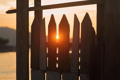 Close-up of silhouette fence against orange sky