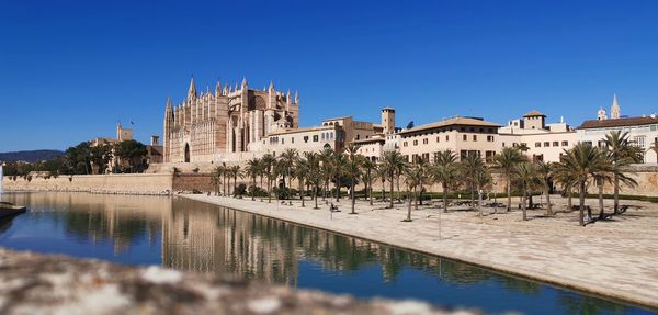 Panoramic view of river by buildings against clear blue sky