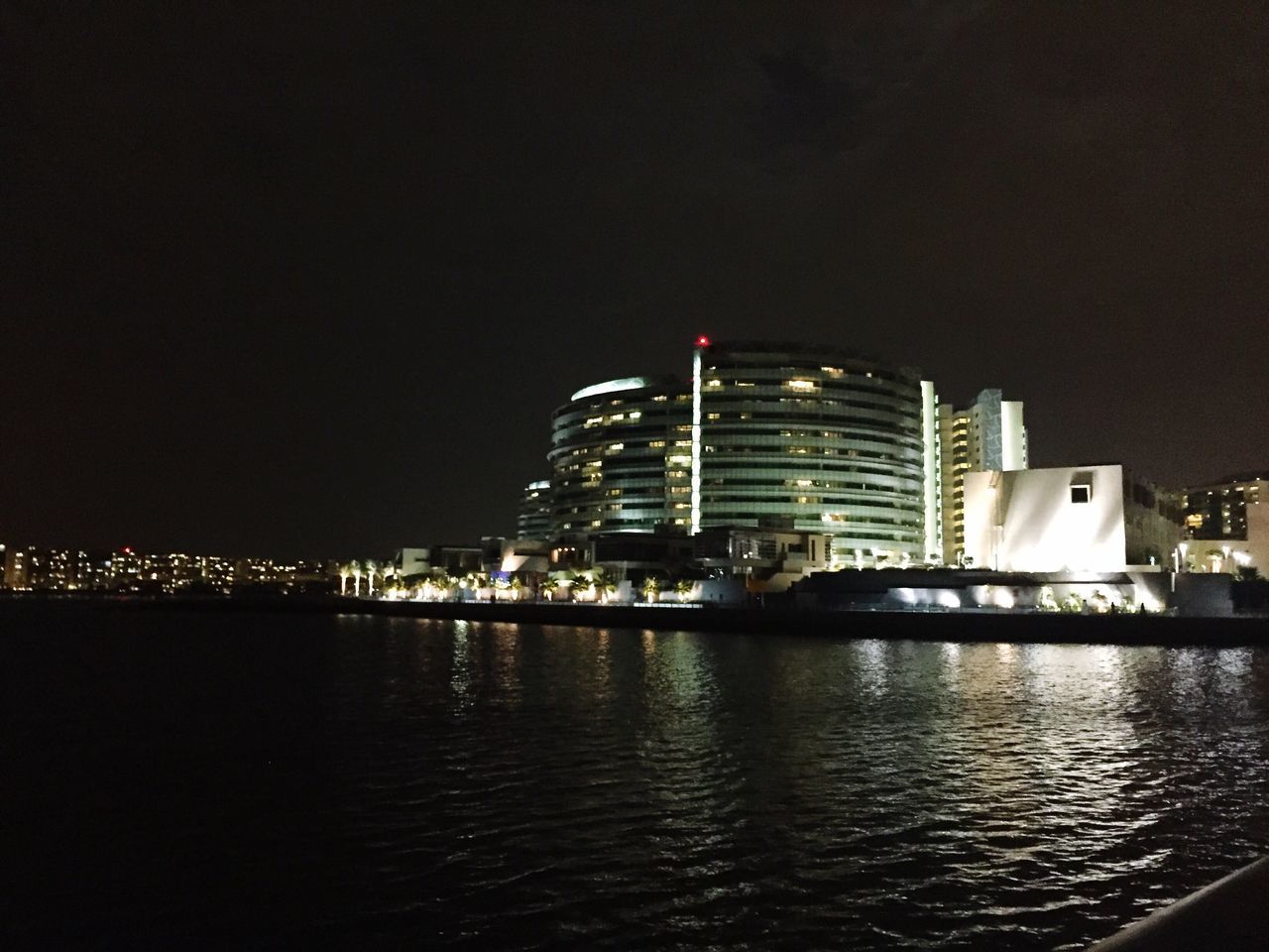 illuminated, building exterior, night, city, architecture, built structure, cityscape, skyscraper, water, waterfront, urban skyline, river, modern, office building, reflection, sky, sea, tall - high, tower, financial district