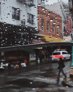 Cars on road seen through wet window in rainy season