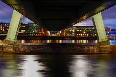 Illuminated bridge over river against sky in city at night