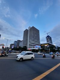 Traffic on city street by buildings against sky