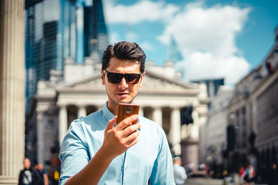Portrait of young man wearing sunglasses standing in city