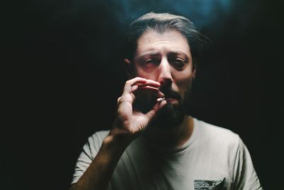 Close-up of man smoking against black background