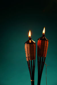 Close-up of illuminated tiki torches against green background