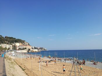 Tourists on beach playing beach volleyball