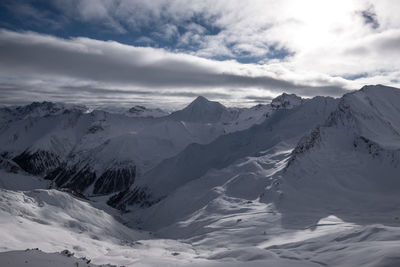 Scenic view of snowy mountains against cloudy sky