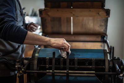 Midsection of man cleaning machinery in factory