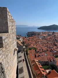 High angle view of townscape by sea against clear blue sky