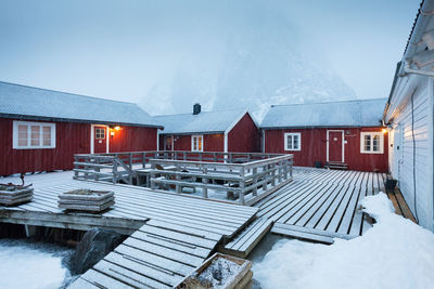 Snow covered houses by buildings against sky during winter