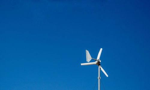 Low angle view of wind turbine against blue sky