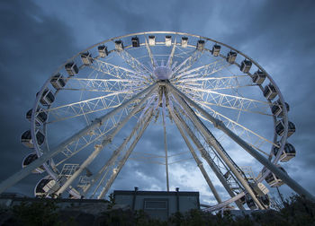 Low angle view of ferris wheel against cloudy sky at dusk