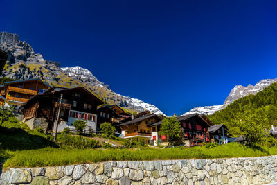 Houses and trees against clear blue sky