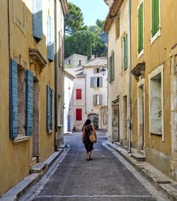 Rear view of woman walking on street amidst buildings in city