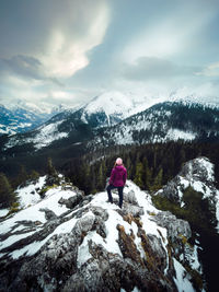 Rear view of woman standing on snowcapped mountain