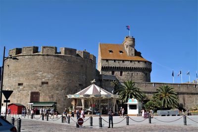 Group of people at historical building against clear blue sky