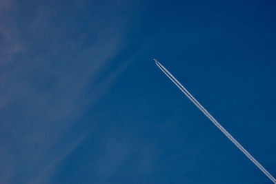 Low angle view of vapor trail against blue sky