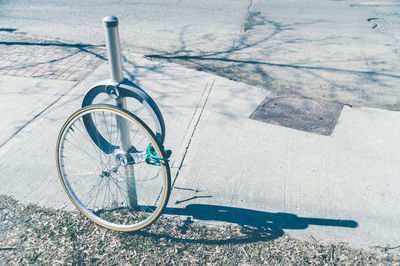 High angle view of bicycle tire by pole on sidewalk