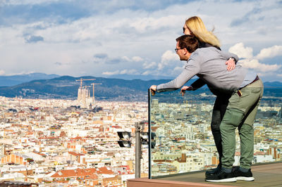 Couple looking at cityscape while standing on balcony