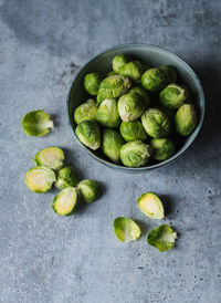 Overhead view of bowl of brussels sprouts on cement counter.