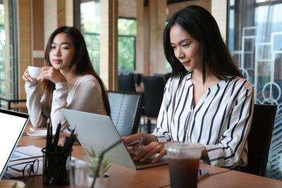 Young woman using phone while sitting on table