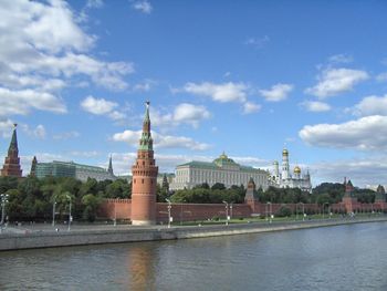 View of city at waterfront against cloudy sky