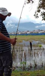 Man fishing at shore against sky