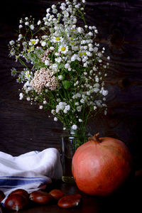 Close-up of pomegranate by flowers on table