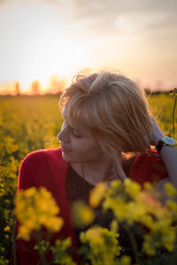 Close-up of beautiful woman with flowers in field against sky