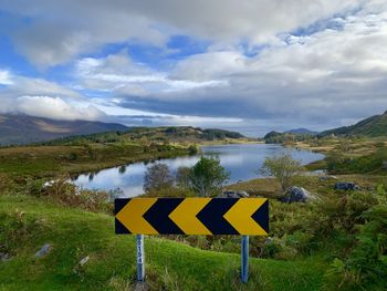 Scenic view of sign by lake against sky