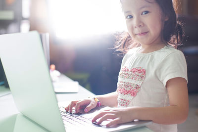 Portrait of smiling cute girl using laptop at home