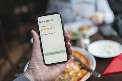 Person holding smart phone with restaurant rating app