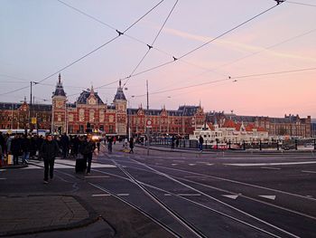 People on railroad tracks against sky during sunset