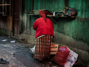 Rear view of woman standing against red wall