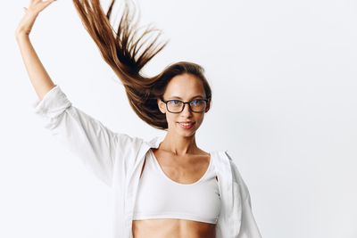 Young woman with arms raised standing against white background