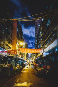 Illuminated city street against sky at night