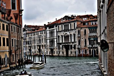 Canal amidst buildings in city against sky