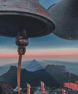 Low angle view of metal hanging by sea against mountains