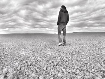 Rear view of man walking on field against sky