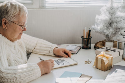 Healthy new years resolutions for older adults. senior mature old woman in white sweater writing