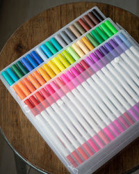 60 pieces of colorful markers in transparent plastic packaging on a wooden background.