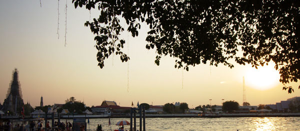 Scenic view of river by city against sky at sunset