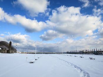 Snow covered landscape against cloudy sky