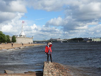 Man standing on beach against cloudy sky