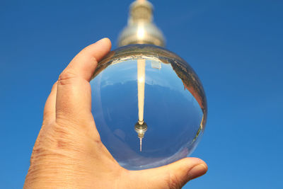 Cropped hand holding crystal ball against fernsehturm