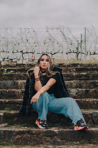 Full length portrait of young woman sitting outdoors