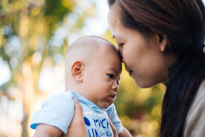 Mother kissing baby boy in park