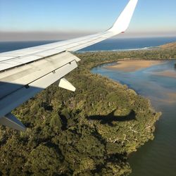 Close-up of airplane flying over landscape against sky