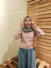 Portrait of a smiling girl standing against wall