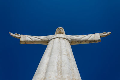 Low angle view of jesus christ statue against blue sky, lubango, angola